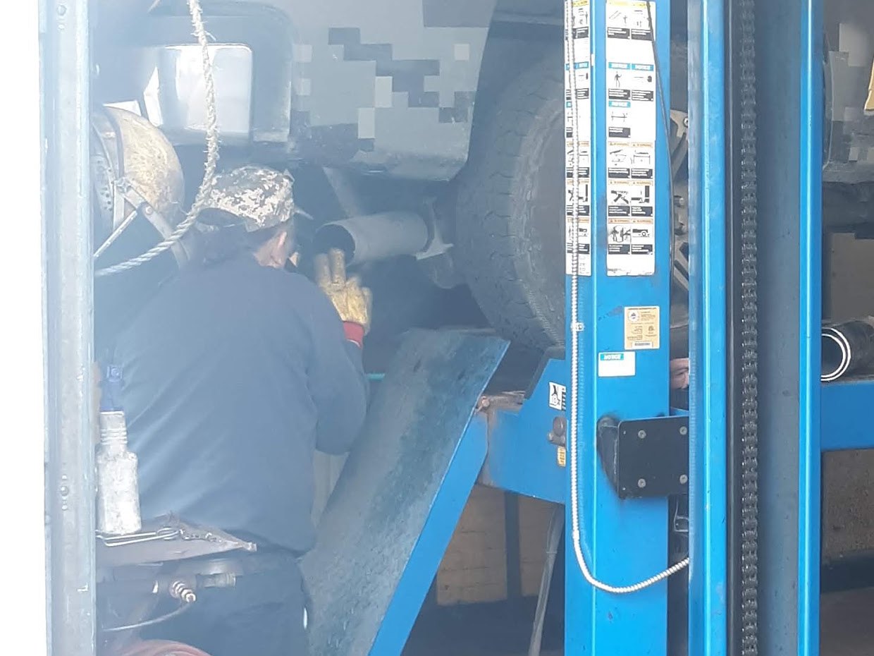 A mechanic working on a truck's exhaust at A-1 Muffler Shop